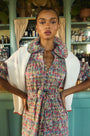 An open V-neckline with a ruffled collar, elbow length puff sleeves with tie details.