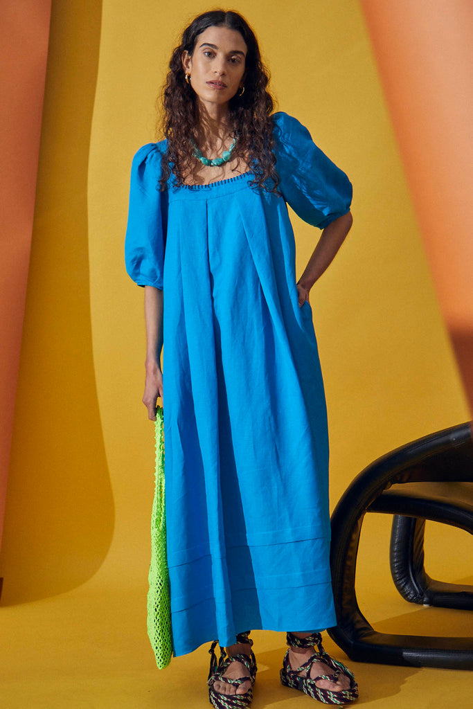 The Waverly is a trapeze maxi dress with a square neckline, elbow length balloon sleeves and pleats.