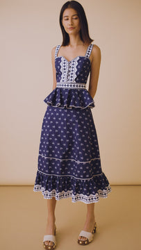 The Lacey Dress has a sweetheart neckline, a fitted bodice, peplum hem, and painted flower buttons.