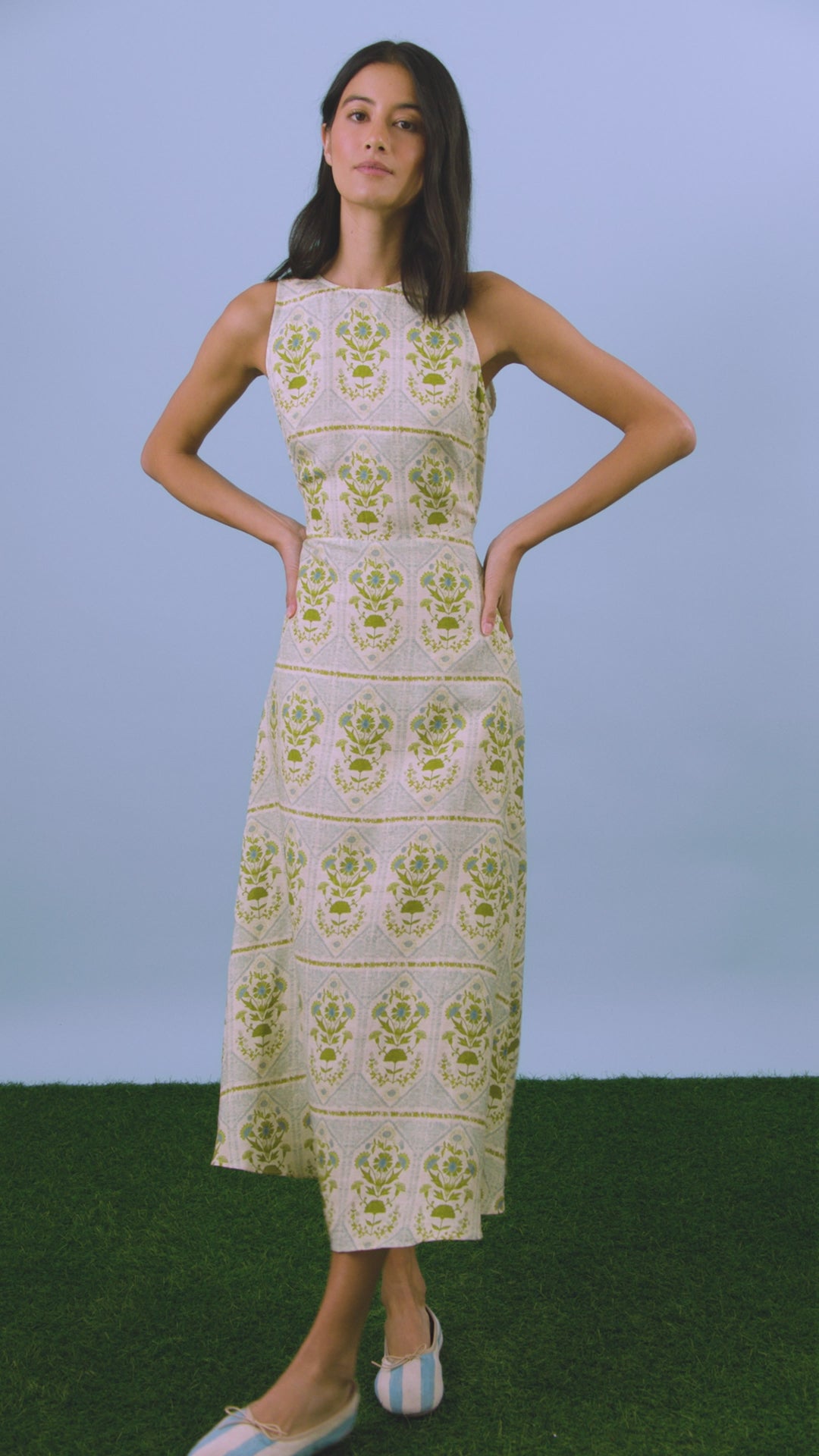 Faith Dress in Green Trellis modeled in front of blue wall.
