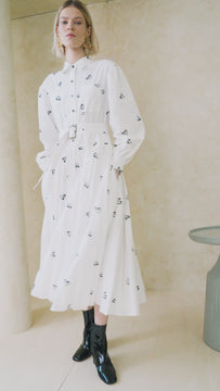 An embroidered shirt dress with a fitted yoke at the waist, a pleated skirt and an optional belt.