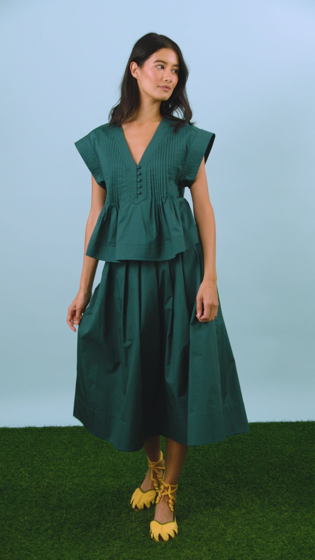 A cropped, boxy top, v-neckline, delicate pintuck detailing and short banded sleeve in petrol green.