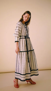 A long sleeve maxi dress with adorned fringe, and a textured pattern with large blouson sleeves.