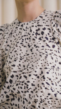 The Harris animal print top has a round neckline, long sleeves, puff shoulders and a shirttail hem.