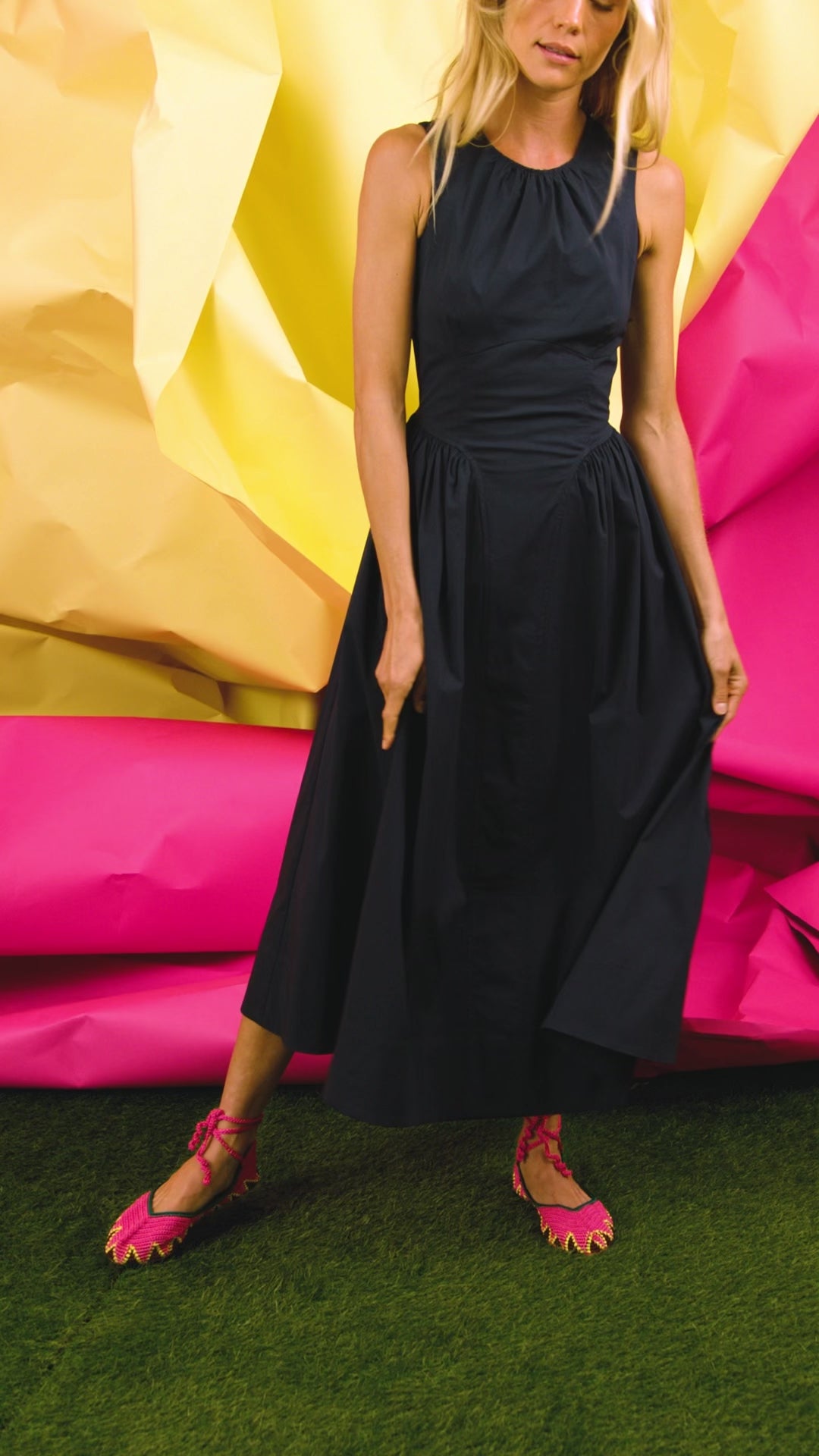 A sleeveless midi navy dress with a fitted bustier bodice, crew neckline, and a bustled full skirt.
