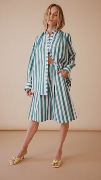 The Marquese features a pleated waist and wide, cropped trouser legs in emerald stripe.