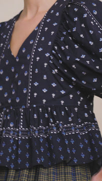The Landry top has a deep v-neck and puff sleeves, a peplum hem and center back zipper.