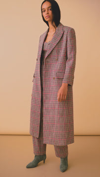 The houndstooth travel coat has a collared neck with peaked lapels and a double breasted silhouette.