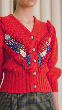 The Spencer sweater has a v-neck front with intricate knit embroidery and turquoise buttons.