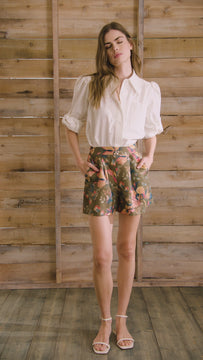 White linen long-sleeve collared shirt with roll-tab sleeves and pearl embellishments.