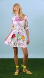 A mini dress with colorful print, front-buttons, mandarin collar, and elbow length sleeves with ties.